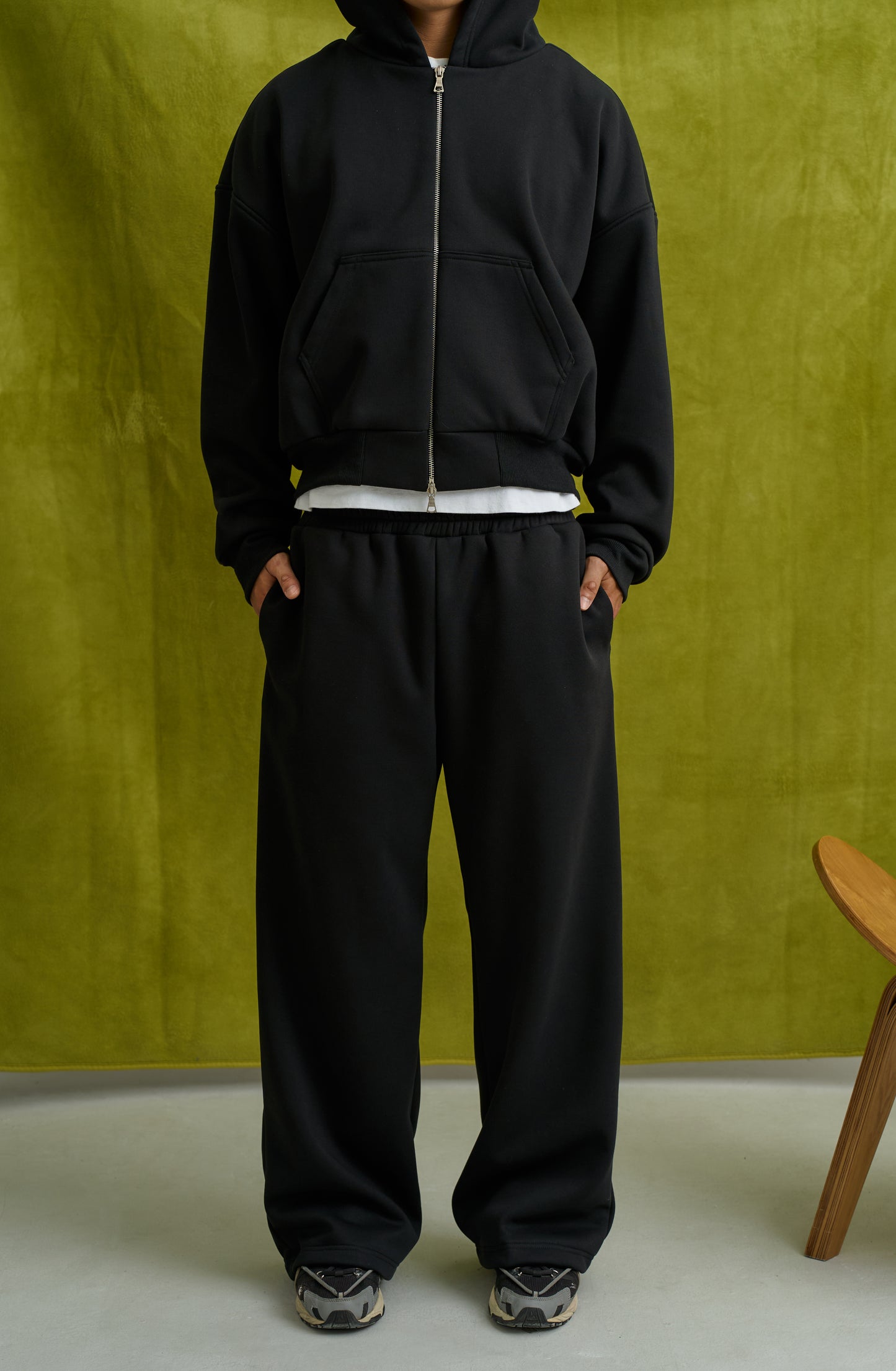 Person wearing a black tracksuit against a green background